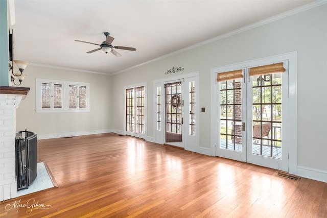 doorway with light hardwood / wood-style floors, ornamental molding, a brick fireplace, and ceiling fan