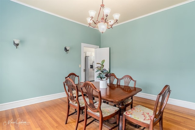 dining area with a notable chandelier, crown molding, and light wood-type flooring