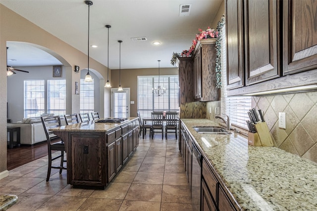 kitchen with a breakfast bar area, ceiling fan with notable chandelier, a healthy amount of sunlight, and tasteful backsplash