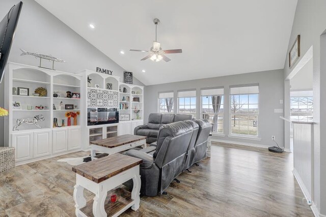 kitchen with a kitchen island with sink, white cabinets, stainless steel refrigerator, plenty of natural light, and light hardwood / wood-style flooring