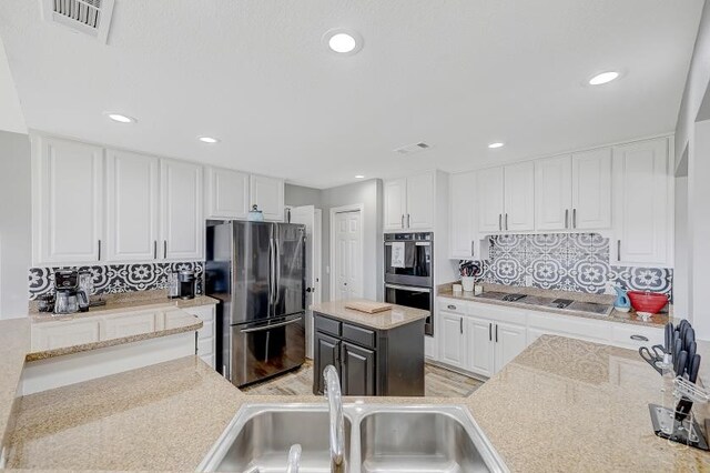 kitchen with a kitchen island, tasteful backsplash, stainless steel appliances, and white cabinetry