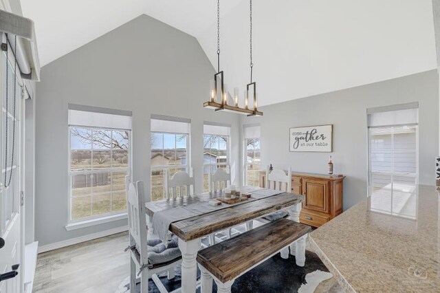 dining space featuring a chandelier, high vaulted ceiling, and light wood-type flooring