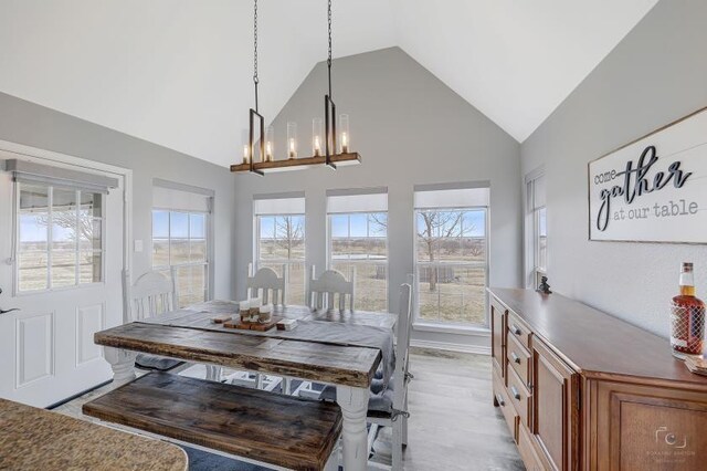 dining room featuring high vaulted ceiling, a notable chandelier, and light hardwood / wood-style floors