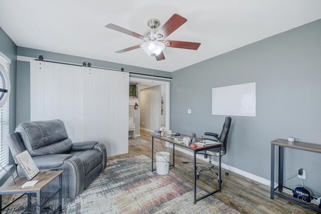 office area with ceiling fan, hardwood / wood-style flooring, and a barn door