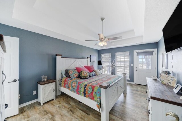 bedroom featuring light hardwood / wood-style flooring, a raised ceiling, and ceiling fan