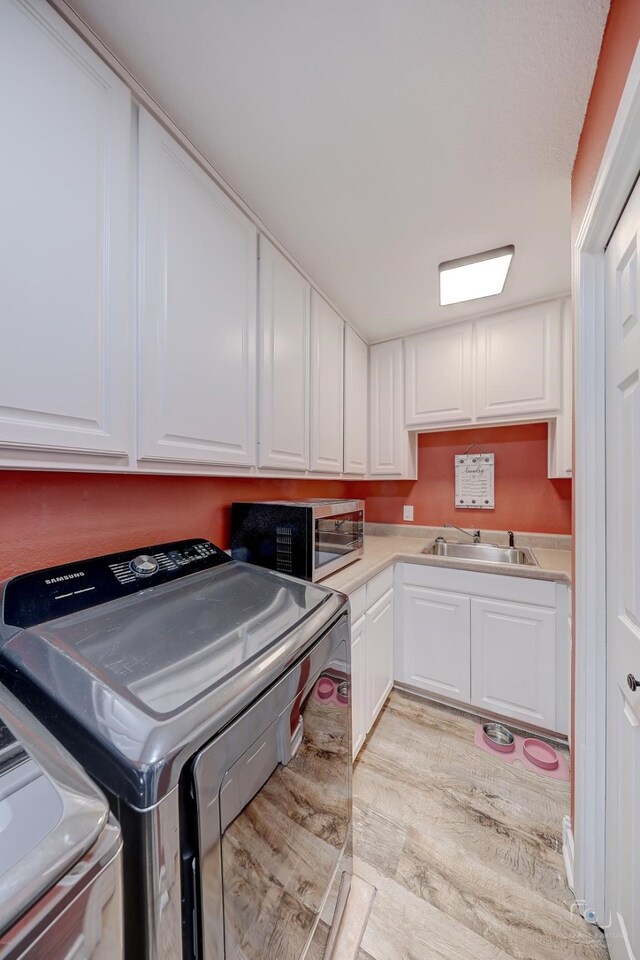 laundry room with sink, washer / clothes dryer, and light wood-type flooring