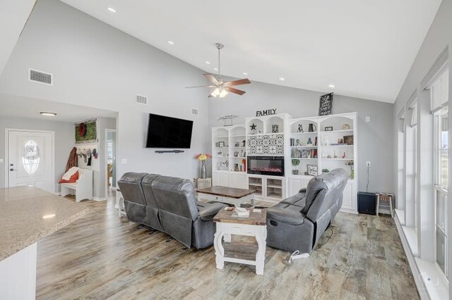 living room featuring high vaulted ceiling, light hardwood / wood-style floors, ceiling fan, and a wealth of natural light