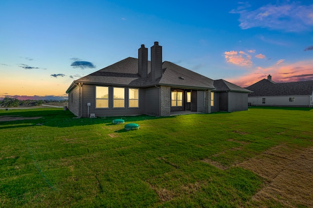 back house at dusk with a lawn