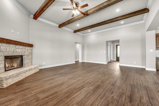 unfurnished living room with dark wood-type flooring, a stone fireplace, ornamental molding, and beam ceiling