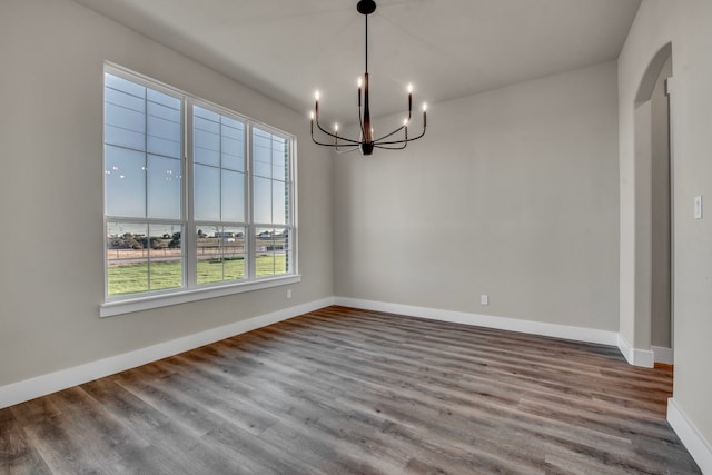 unfurnished dining area with wood-type flooring and a notable chandelier