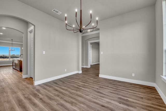 unfurnished dining area with sink, hardwood / wood-style floors, and a notable chandelier