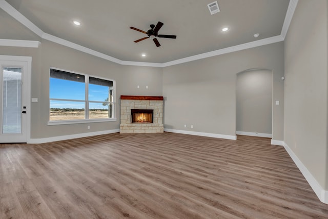 unfurnished living room featuring light wood-type flooring, a fireplace, ceiling fan, and crown molding