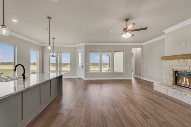 kitchen featuring a fireplace, ceiling fan, decorative light fixtures, ornamental molding, and dark hardwood / wood-style floors