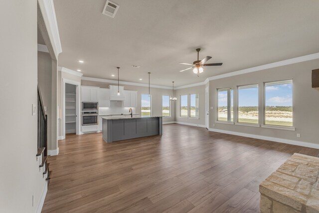 unfurnished living room with ornamental molding, sink, ceiling fan, and hardwood / wood-style flooring