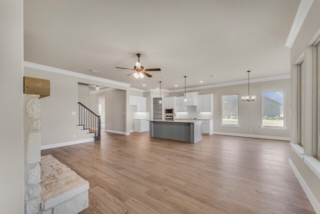 living room featuring ceiling fan with notable chandelier, ornamental molding, and light hardwood / wood-style flooring