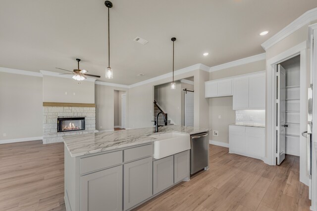 kitchen featuring a barn door, a fireplace, ceiling fan, stainless steel dishwasher, and a kitchen island with sink