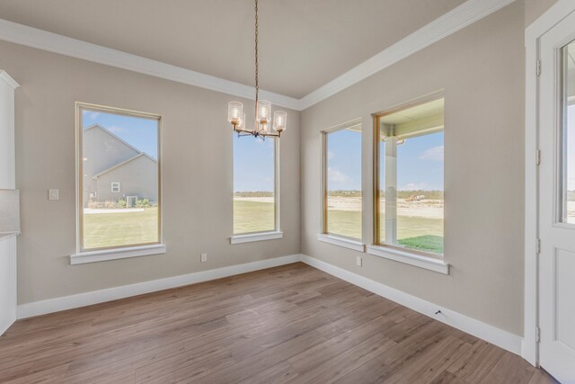 unfurnished dining area featuring an inviting chandelier, crown molding, and light hardwood / wood-style floors