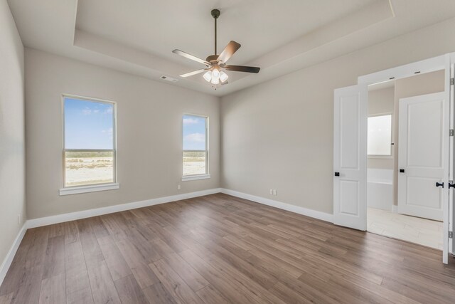 unfurnished room with a tray ceiling, ceiling fan, and hardwood / wood-style floors