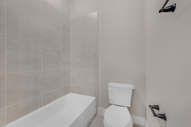 bathroom featuring tiled shower / bath combo, tile patterned flooring, and toilet