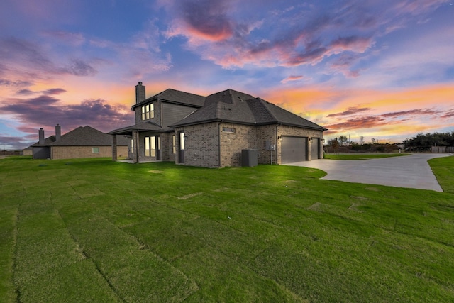 property exterior at dusk with central air condition unit, a yard, and a garage