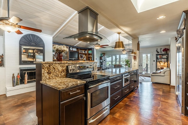 kitchen featuring a fireplace, stainless steel electric range oven, island exhaust hood, open floor plan, and light stone countertops