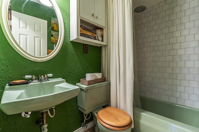 bathroom with shower / tub combo with curtain, a sink, a textured wall, and toilet