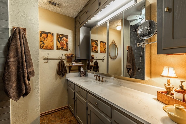 full bathroom featuring a textured ceiling, a textured wall, vanity, and visible vents