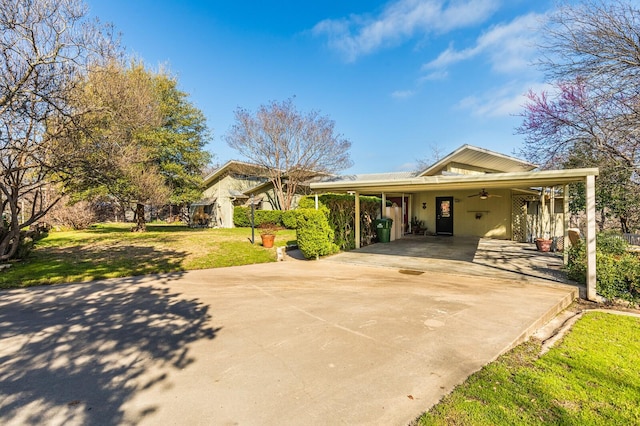 view of front of home with concrete driveway, an attached carport, a front yard, and a ceiling fan