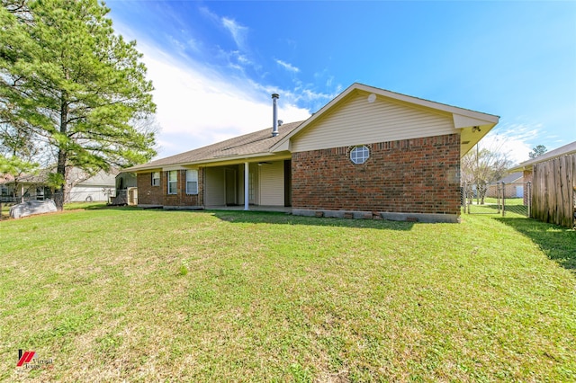 back of property with brick siding, a lawn, and fence