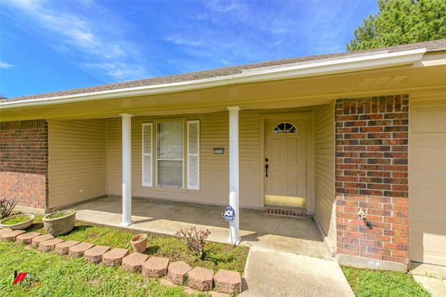 entrance to property featuring covered porch and a garage