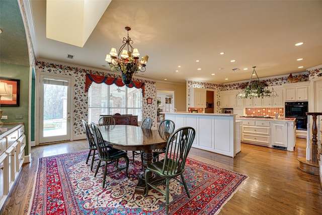 dining room with crown molding, a notable chandelier, and light wood-type flooring