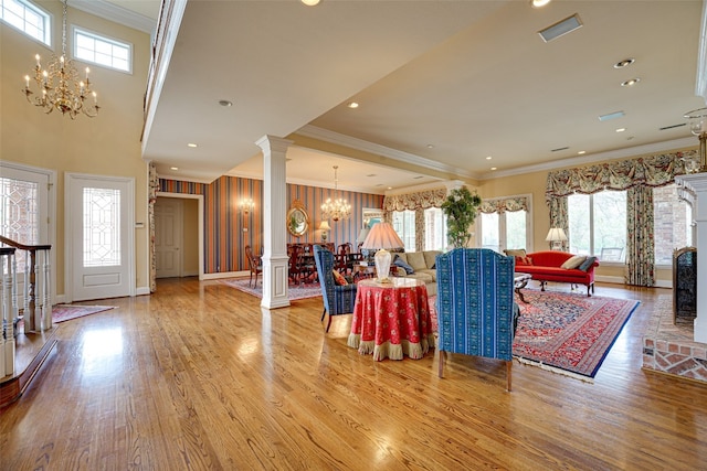 living room with a notable chandelier, light hardwood / wood-style flooring, ornate columns, and plenty of natural light