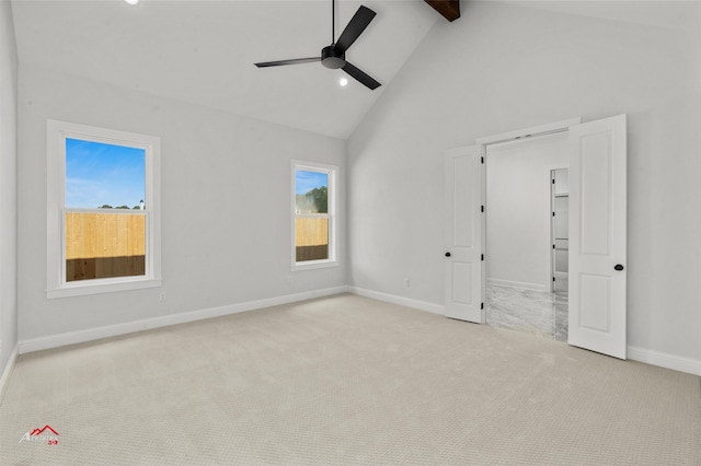 empty room featuring beam ceiling, high vaulted ceiling, ceiling fan, and light colored carpet