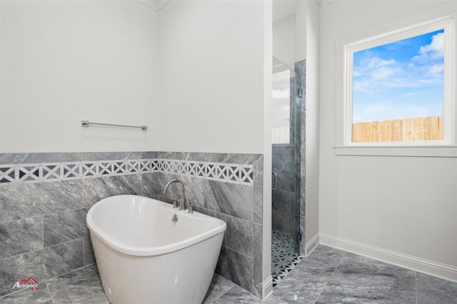 bathroom with a wealth of natural light, tile walls, and tile floors