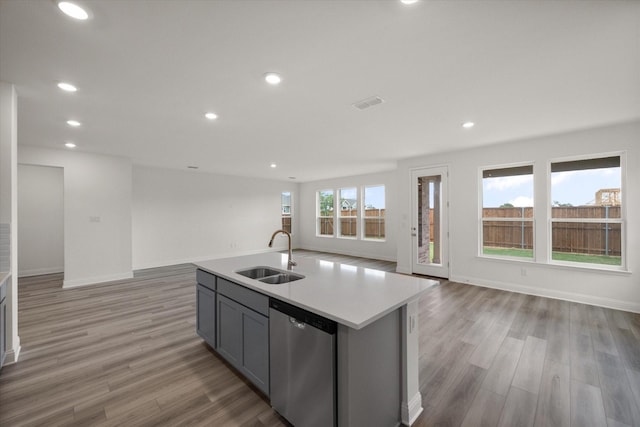 kitchen featuring dishwasher, sink, plenty of natural light, gray cabinets, and a center island with sink