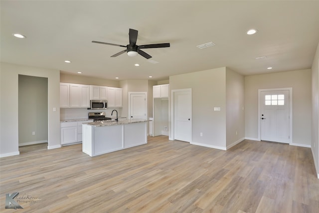 kitchen with appliances with stainless steel finishes, light hardwood / wood-style flooring, sink, light stone countertops, and ceiling fan