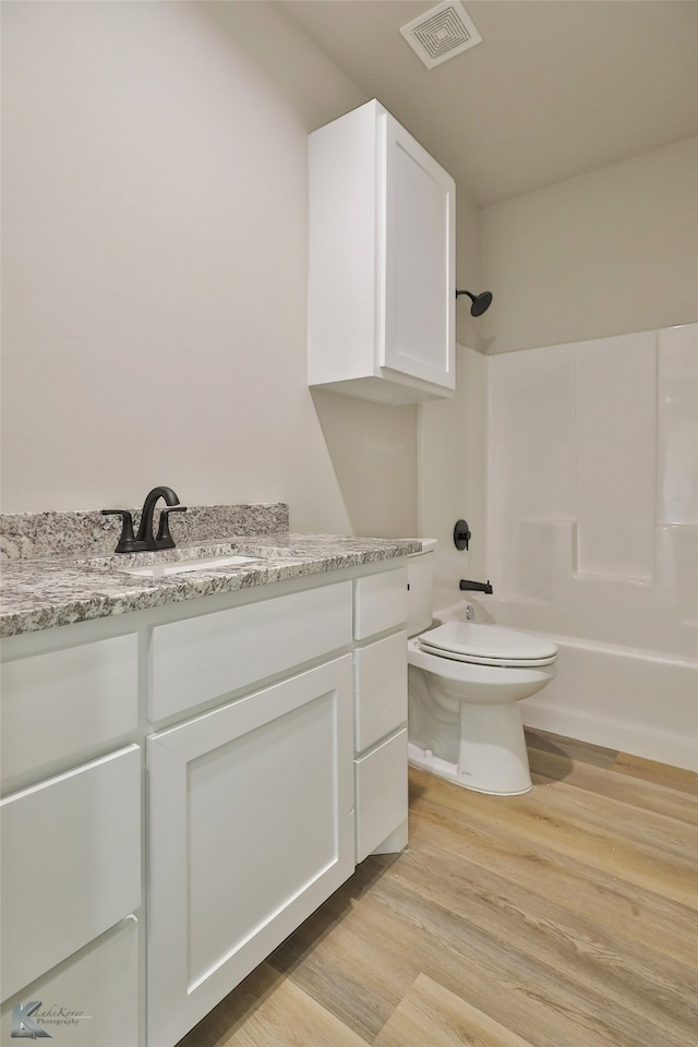 full bathroom featuring bathing tub / shower combination, toilet, hardwood / wood-style floors, and vanity