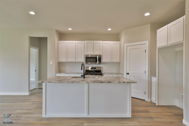 kitchen with sink, stainless steel appliances, decorative backsplash, and light wood-type flooring