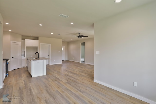 interior space featuring sink, light hardwood / wood-style flooring, and an island with sink