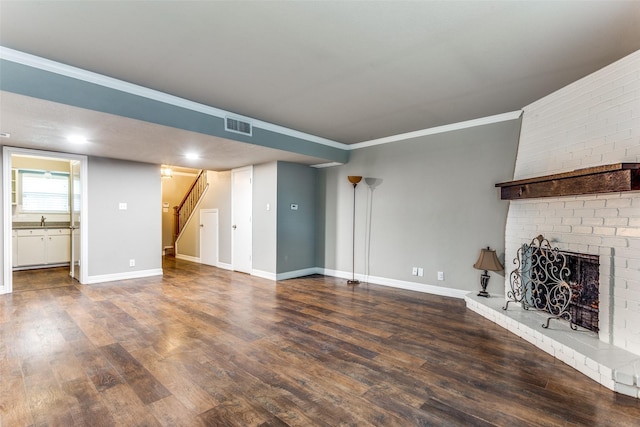 unfurnished living room featuring wood finished floors, baseboards, visible vents, and stairway