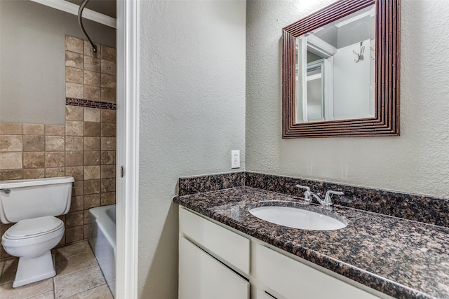 full bathroom featuring a textured wall, vanity, toilet, and tile walls