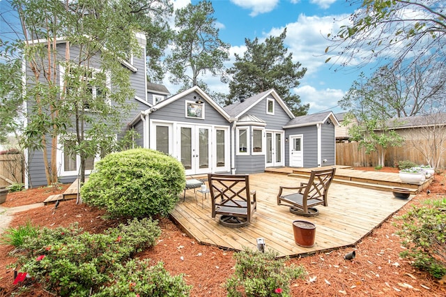 back of property with a wooden deck, a chimney, fence, and french doors