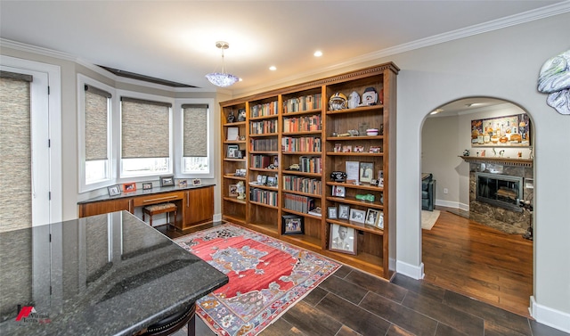 office featuring baseboards, arched walkways, a fireplace with flush hearth, ornamental molding, and dark wood-type flooring