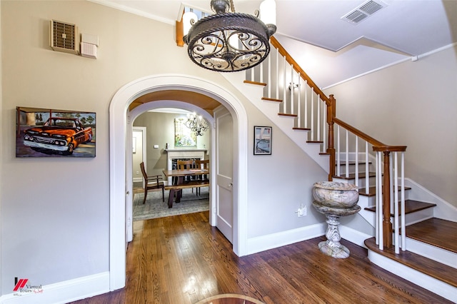 staircase featuring arched walkways, visible vents, wood finished floors, a chandelier, and baseboards