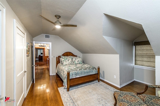 bedroom with a textured ceiling, baseboards, wood finished floors, and lofted ceiling