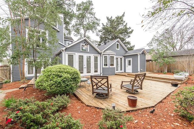 back of property with a chimney, french doors, fence, and a deck