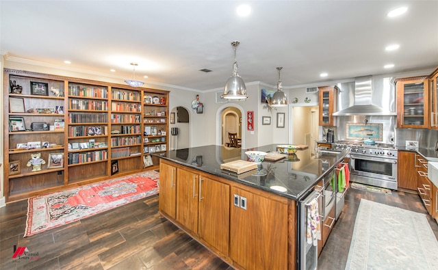 kitchen with range with two ovens, wall chimney exhaust hood, brown cabinets, and a center island