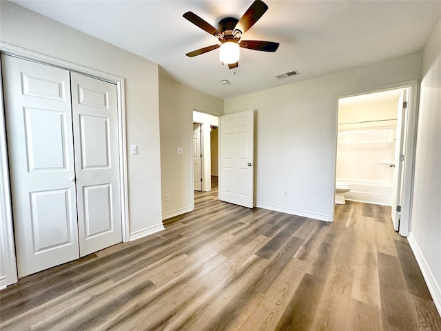 unfurnished bedroom featuring ceiling fan, a closet, dark wood-type flooring, and connected bathroom