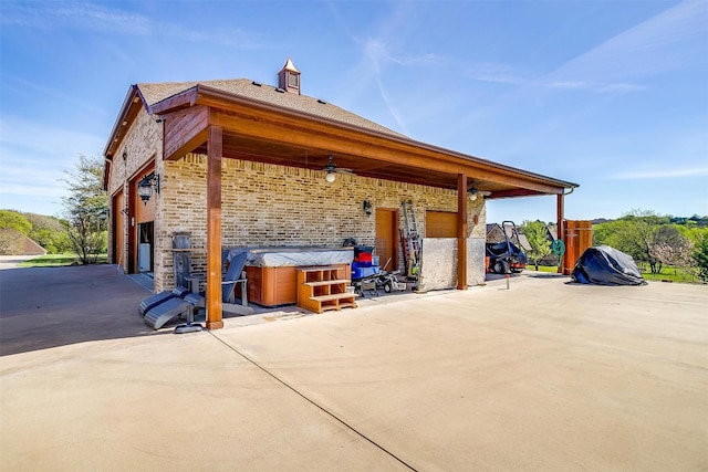 view of side of home with a hot tub, a patio, and ceiling fan