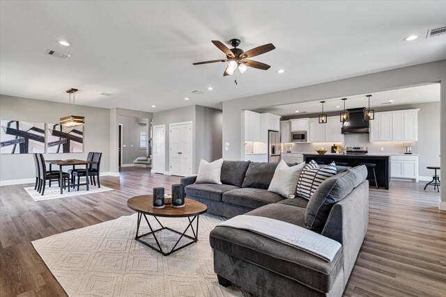 living room with ceiling fan and light wood-type flooring